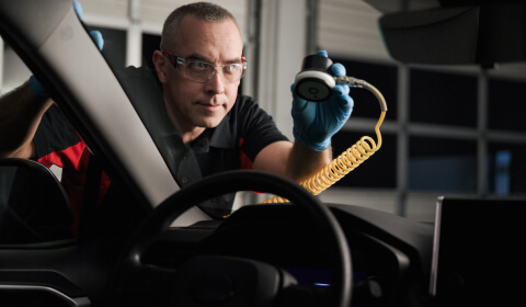 A Safelite technician performing a repair on a vehicle windshield