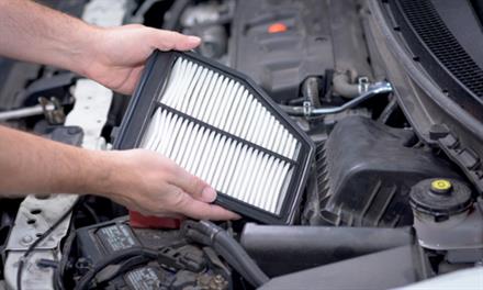 mechanic placing new air filter in car