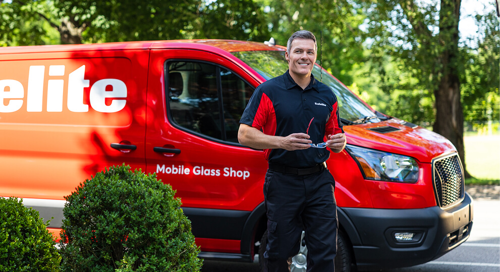 A Safelite technician in front of a mobile glass shop vehicle.