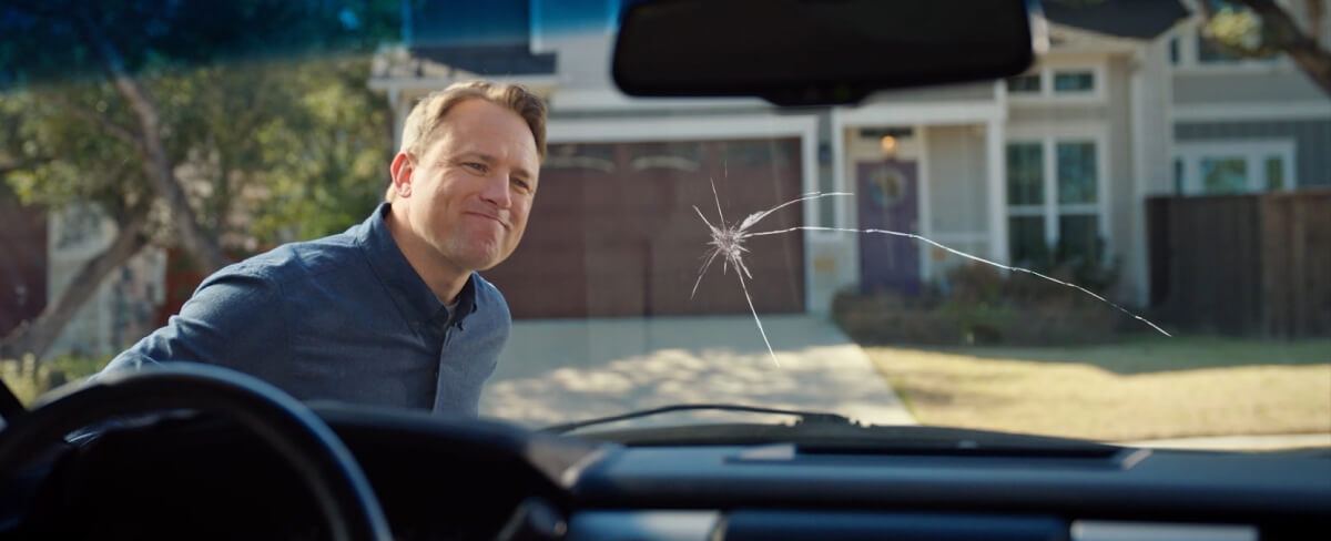 A person looking at a crack in their vehicle’s windshield